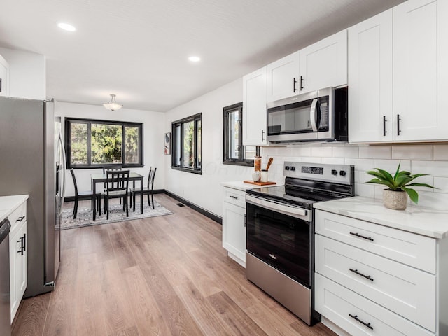 kitchen featuring tasteful backsplash, white cabinetry, appliances with stainless steel finishes, and light hardwood / wood-style flooring