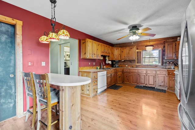 kitchen featuring decorative backsplash, light hardwood / wood-style floors, a kitchen bar, and white appliances