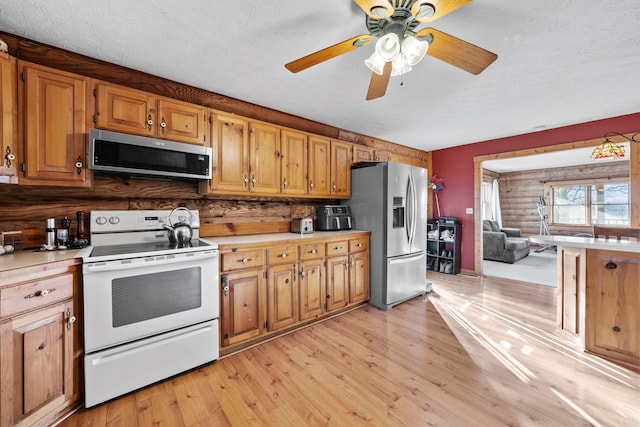 kitchen with ceiling fan, backsplash, a textured ceiling, appliances with stainless steel finishes, and light wood-type flooring