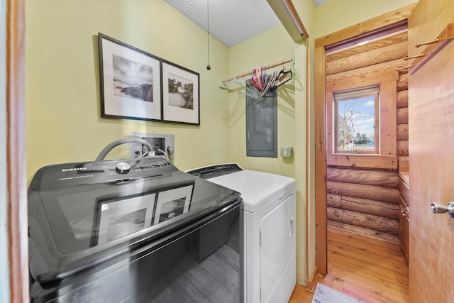 laundry room featuring light hardwood / wood-style floors, separate washer and dryer, a textured ceiling, and log walls