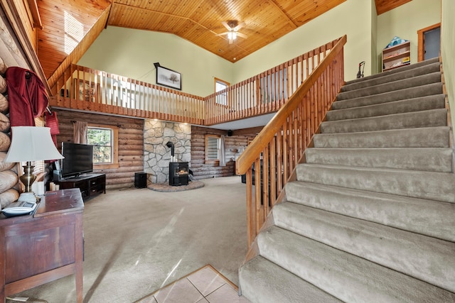 living room with a wood stove, ceiling fan, high vaulted ceiling, and wood ceiling