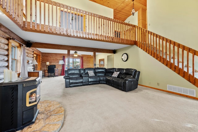 carpeted living room with a wood stove, ceiling fan, and high vaulted ceiling