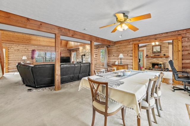 carpeted dining area with wood walls, ceiling fan, a fireplace, and a textured ceiling