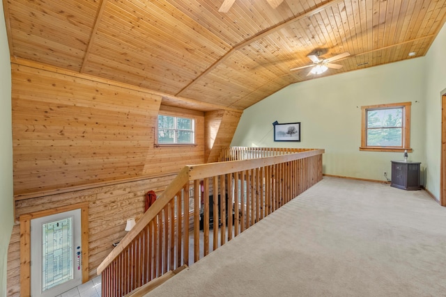 hall featuring lofted ceiling, wood walls, light colored carpet, and wooden ceiling