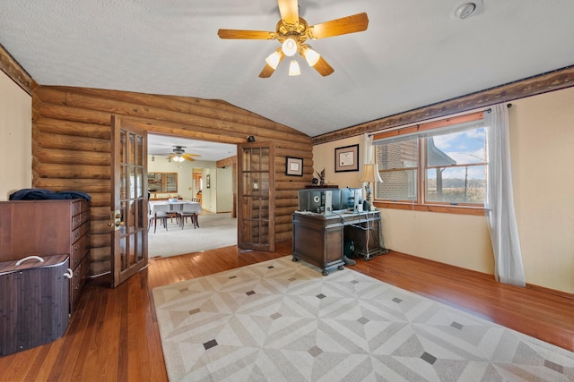 office space featuring ceiling fan, log walls, wood-type flooring, and lofted ceiling