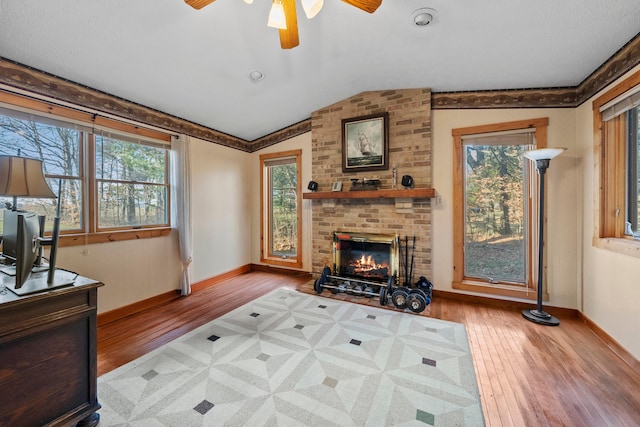 living room featuring hardwood / wood-style flooring, a fireplace, a wealth of natural light, and vaulted ceiling