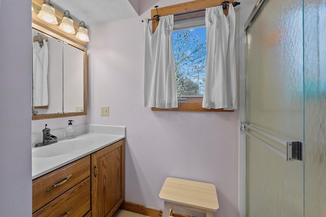 bathroom with vanity, a shower with shower door, and a textured ceiling