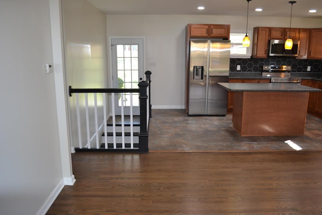 kitchen with a center island, dark hardwood / wood-style floors, backsplash, decorative light fixtures, and appliances with stainless steel finishes