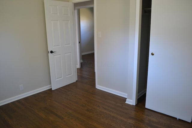 unfurnished bedroom with dark hardwood / wood-style flooring and a closet