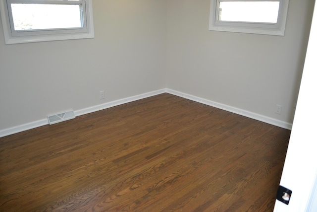 unfurnished room featuring a wealth of natural light and dark wood-type flooring