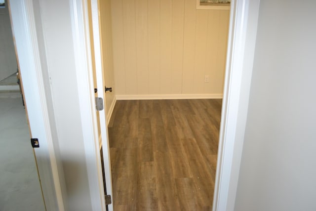 corridor featuring wooden walls and dark hardwood / wood-style flooring