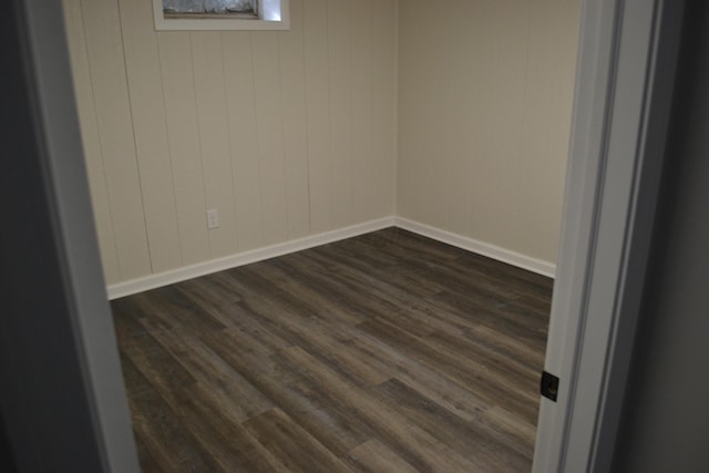 unfurnished room featuring wood walls and dark hardwood / wood-style flooring