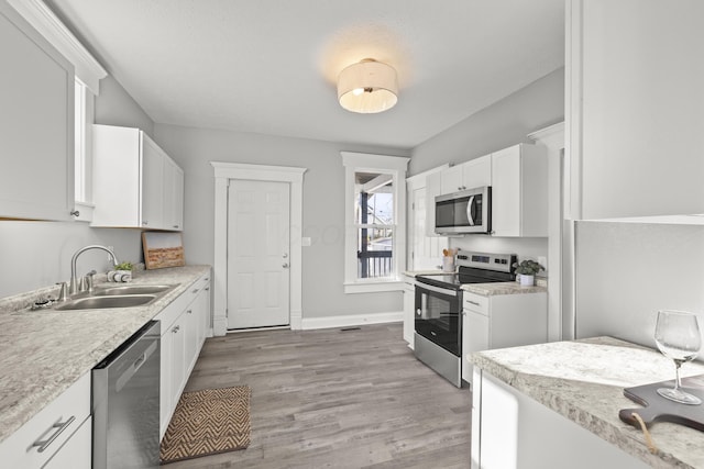 kitchen featuring white cabinetry, sink, stainless steel appliances, and light hardwood / wood-style floors