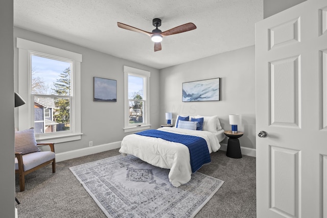 bedroom with a textured ceiling, dark carpet, and ceiling fan