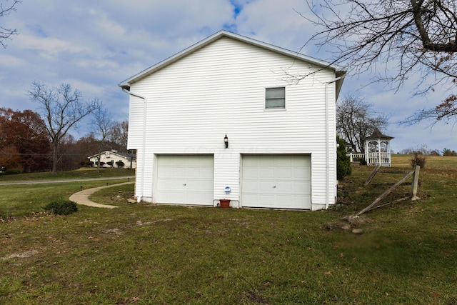 view of side of property featuring a garage and a lawn