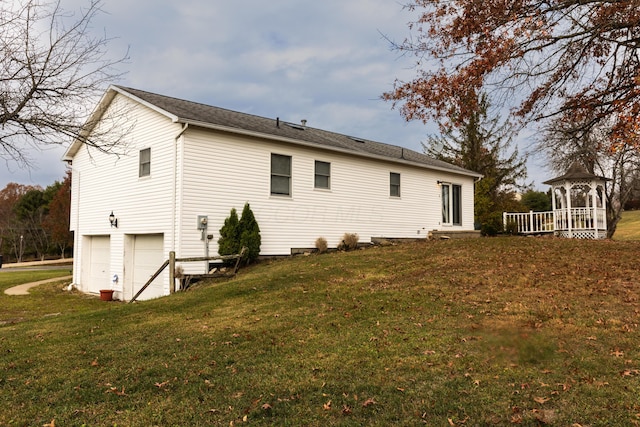 rear view of property featuring a garage and a lawn