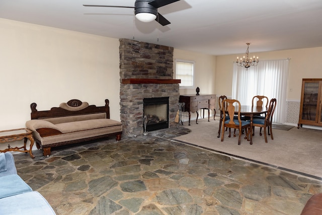 carpeted dining space with a fireplace and ceiling fan with notable chandelier