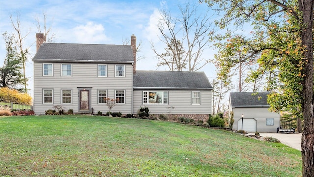 colonial home with a garage, a front lawn, and an outdoor structure