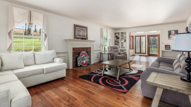 living room with hardwood / wood-style flooring, built in features, a fireplace, and ornamental molding