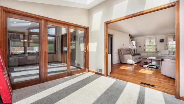 doorway to outside featuring light hardwood / wood-style flooring, lofted ceiling, and a notable chandelier