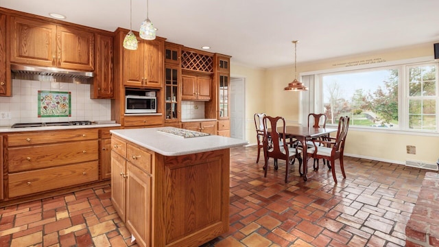 kitchen featuring tasteful backsplash, decorative light fixtures, a kitchen island, and stainless steel gas stovetop