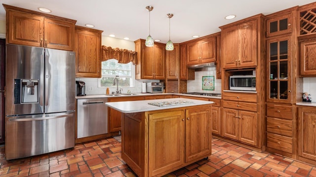 kitchen with decorative backsplash, appliances with stainless steel finishes, sink, decorative light fixtures, and a kitchen island