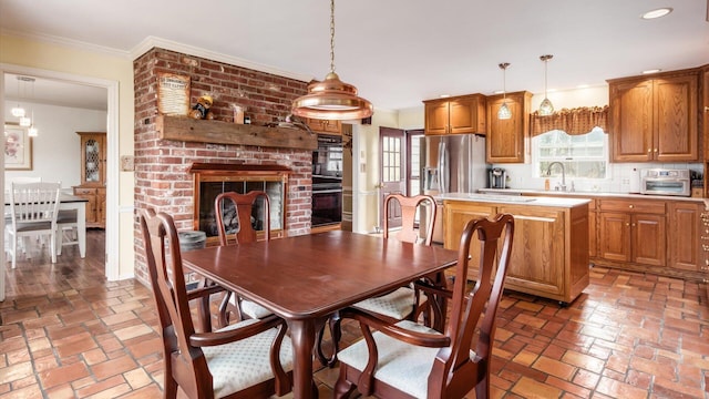 dining space featuring a brick fireplace and crown molding