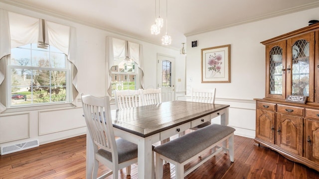 dining space with a healthy amount of sunlight, wood-type flooring, and crown molding