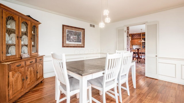 dining area with light hardwood / wood-style floors and ornamental molding