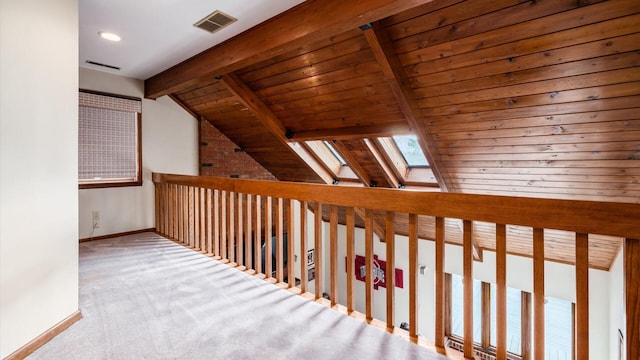 corridor with vaulted ceiling with skylight, wooden ceiling, and light carpet