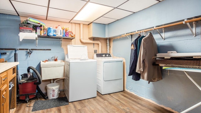 clothes washing area with separate washer and dryer, sink, and light hardwood / wood-style floors