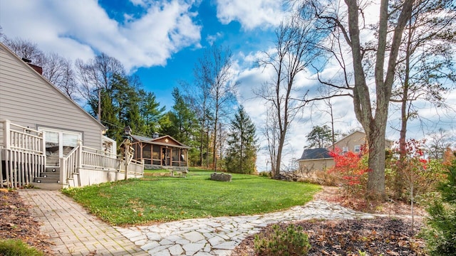 view of yard featuring a sunroom, a fire pit, and a wooden deck