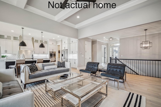 living room featuring ornamental molding, sink, an inviting chandelier, light hardwood / wood-style flooring, and beamed ceiling