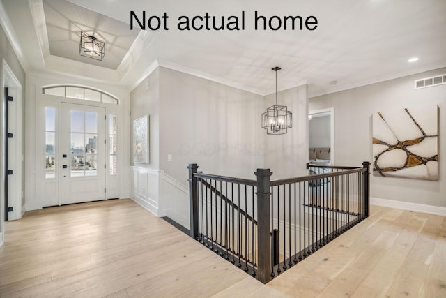 foyer entrance featuring wood-type flooring, an inviting chandelier, and crown molding