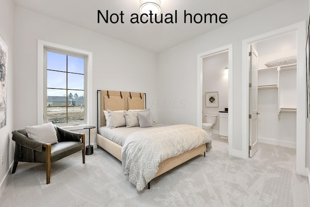 carpeted bedroom featuring a closet, a walk in closet, and ensuite bath