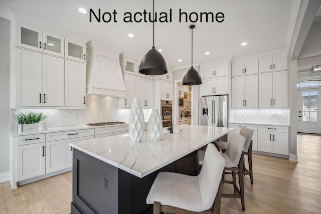 kitchen featuring a center island with sink, white cabinets, stainless steel appliances, and custom range hood