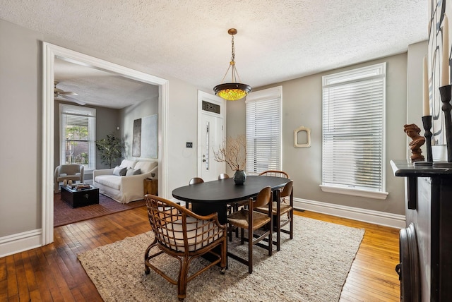 dining space with ceiling fan, hardwood / wood-style floors, and a textured ceiling