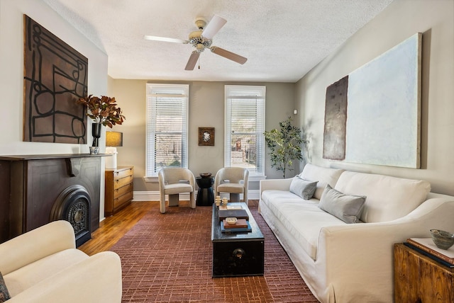 living room featuring ceiling fan, dark hardwood / wood-style flooring, and a textured ceiling