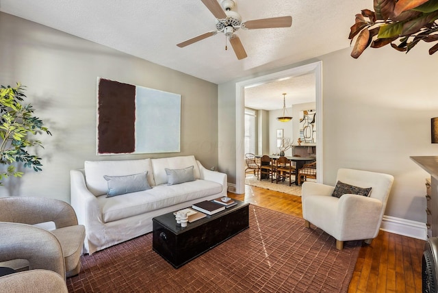 living room with ceiling fan, dark wood-type flooring, and a textured ceiling