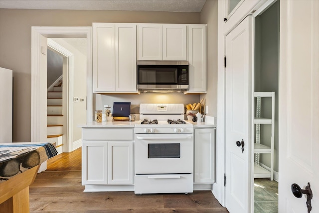 kitchen featuring dark hardwood / wood-style flooring, white cabinetry, a textured ceiling, and gas range gas stove