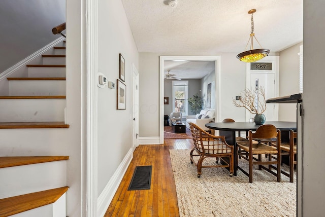 dining space featuring wood-type flooring, a textured ceiling, and ceiling fan