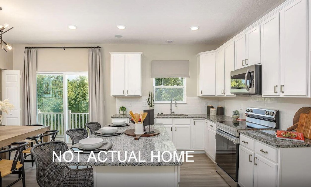 kitchen featuring white cabinets, appliances with stainless steel finishes, and dark stone counters