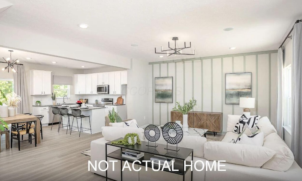 living room with a notable chandelier, sink, and light hardwood / wood-style flooring