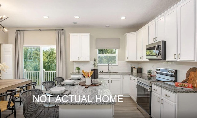 kitchen featuring white cabinetry, stainless steel appliances, and dark stone counters