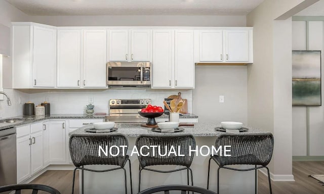 kitchen with light stone counters, white cabinetry, and appliances with stainless steel finishes