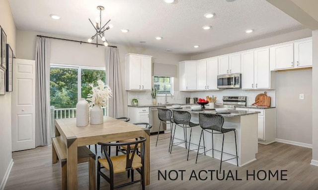 kitchen featuring sink, stainless steel appliances, white cabinets, a kitchen island, and dark stone counters