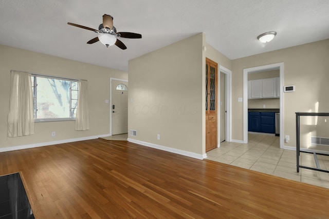 unfurnished living room with ceiling fan, light hardwood / wood-style floors, and a textured ceiling