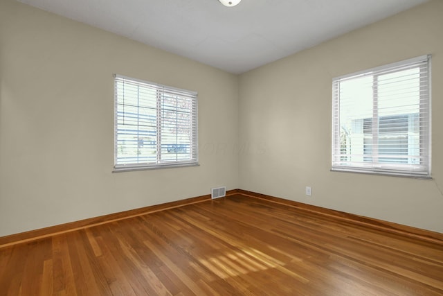 unfurnished room with hardwood / wood-style flooring and plenty of natural light