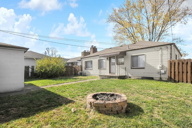 back of property featuring central air condition unit, a yard, and an outdoor fire pit