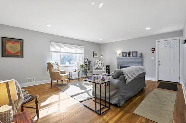 living room with wood-type flooring and a brick fireplace